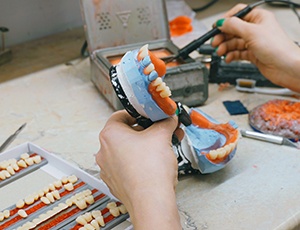 Closeup of lab tech placing pontics into wax dentures