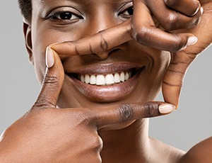 Woman framing her smile with her thumbs and pointers.