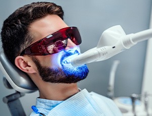 Man with brown hair and beard having teeth whitening at the dentist