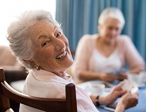 A smiling senior woman playing cards with friends