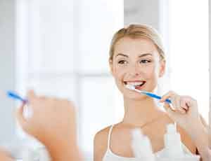 Woman looking in mirror brushing her teeth