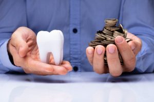 man holding coins and white tooth